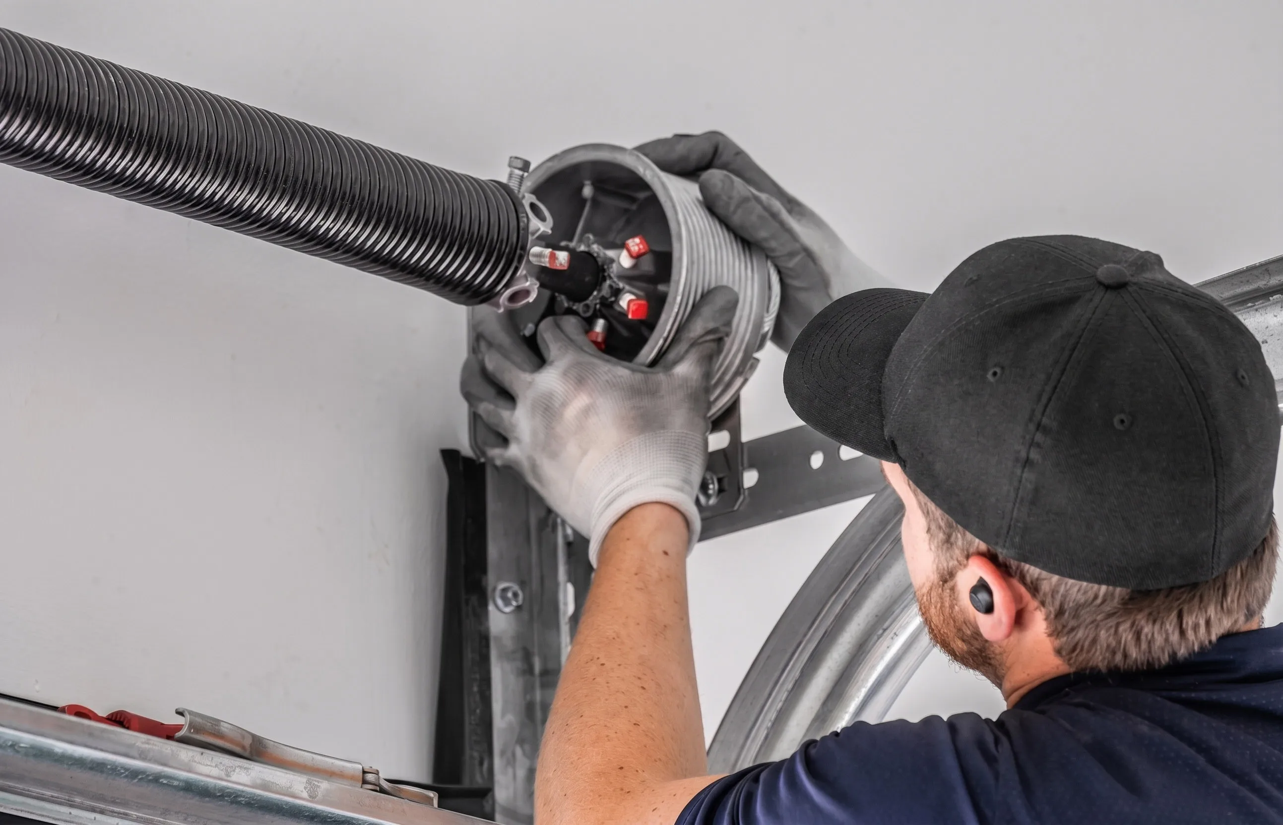 Professional technician servicing a garage door torsion spring during a tune-up.